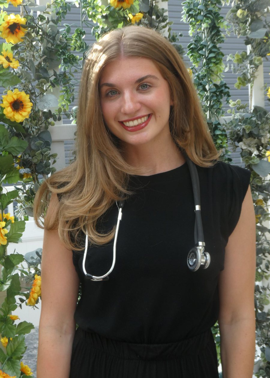 Elyse Fearon, founder of Roots of Hope & Wellness, smiling outdoors with a stethoscope around her neck